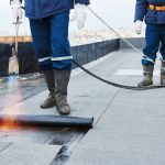 Roofers applying torch down method on a commercial roof in San Antonio for WeatherTech Roofing.